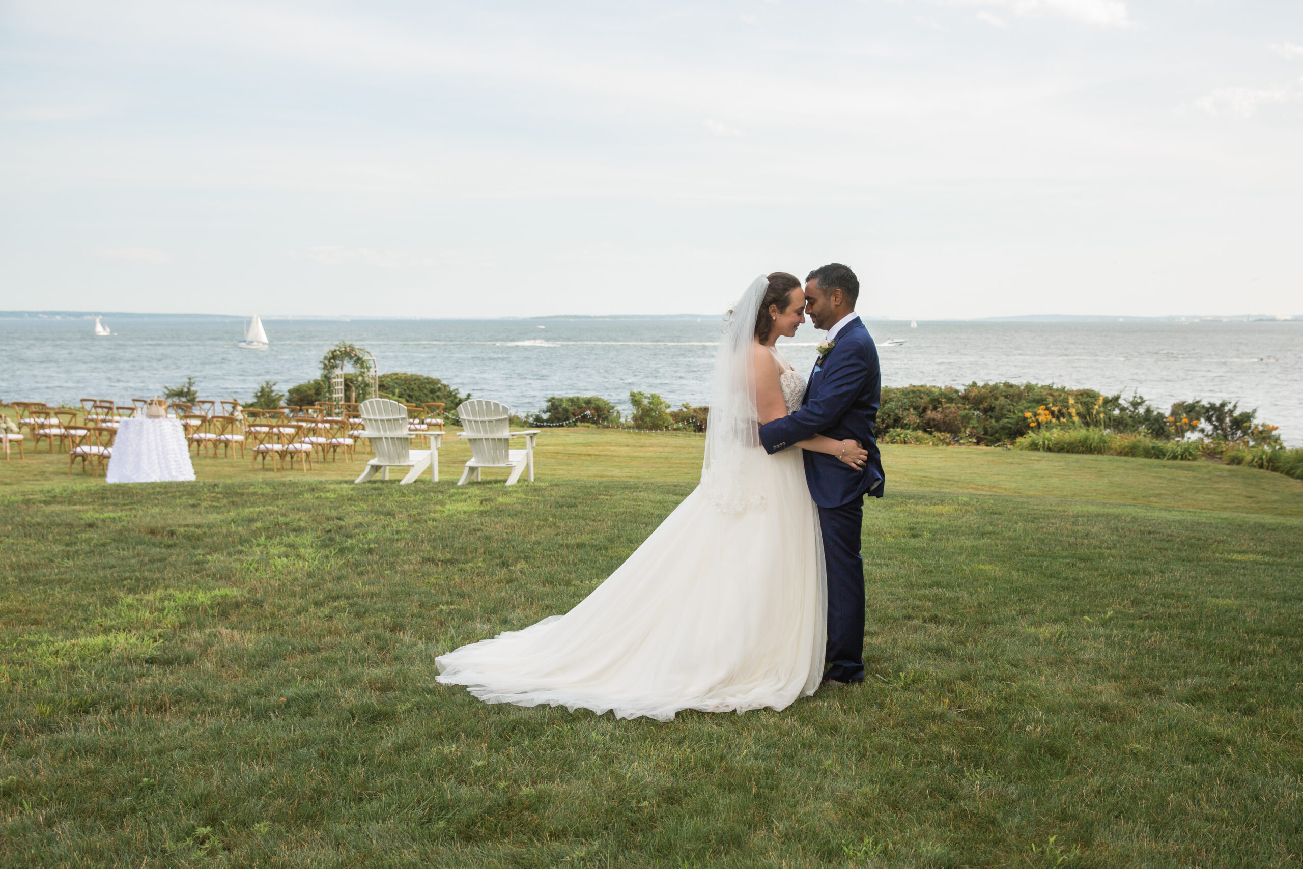 A Bride and Groom embrace on the lawn of their water front wedding.