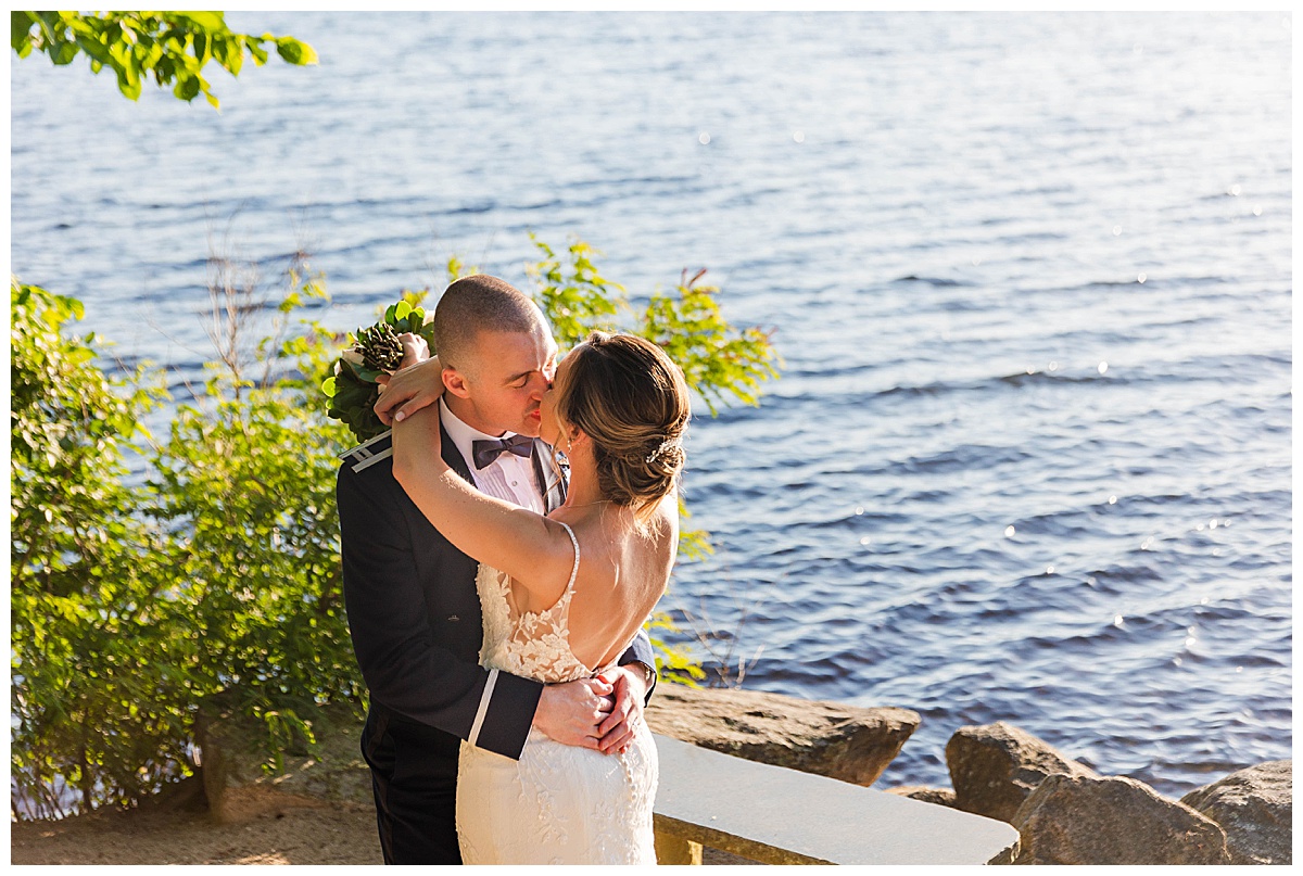 A bride and groom kiss in front of the lake at Saphire Estate 
