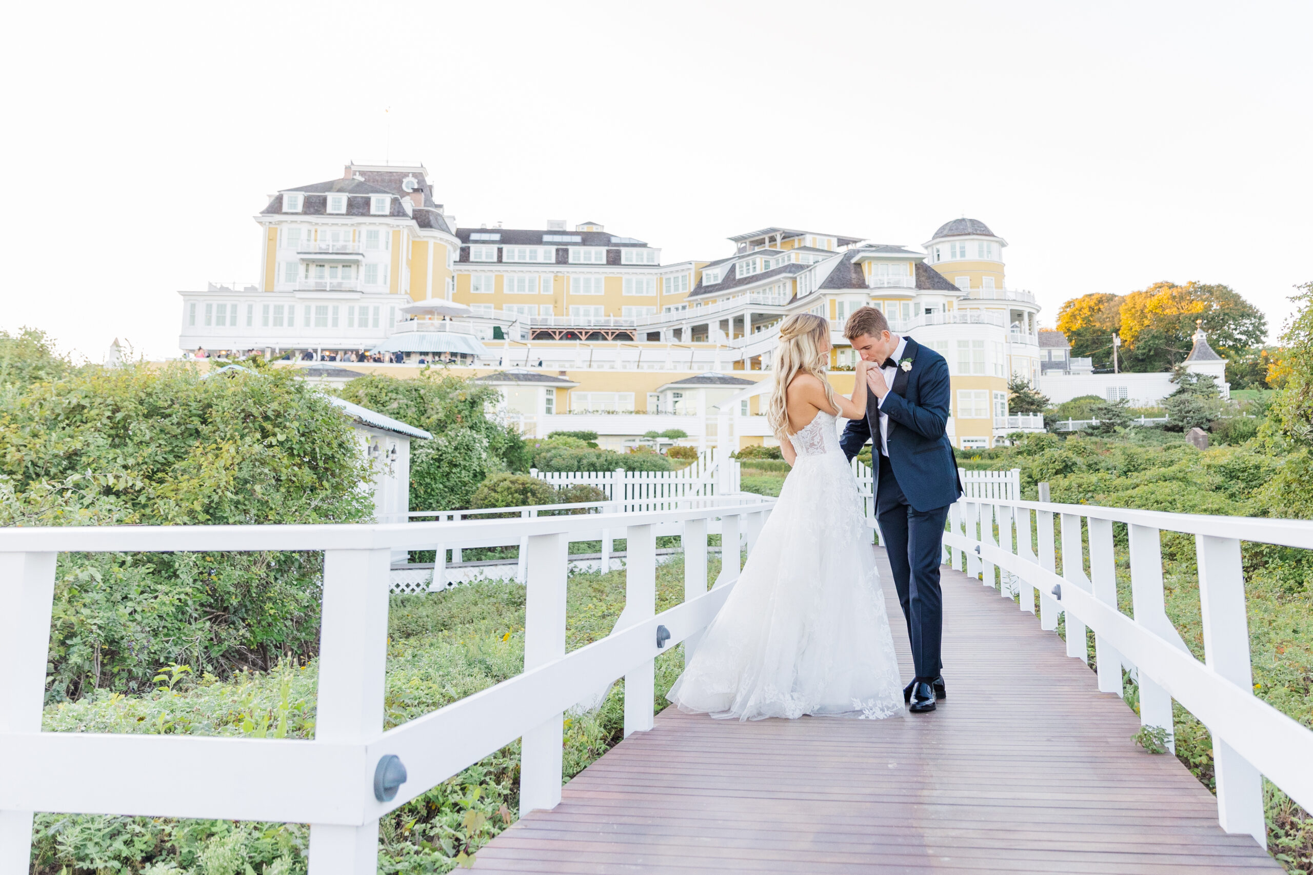 A groom kisses his brides hand on the boardwalk of Ocean House in Watch Hill Rhode Island.