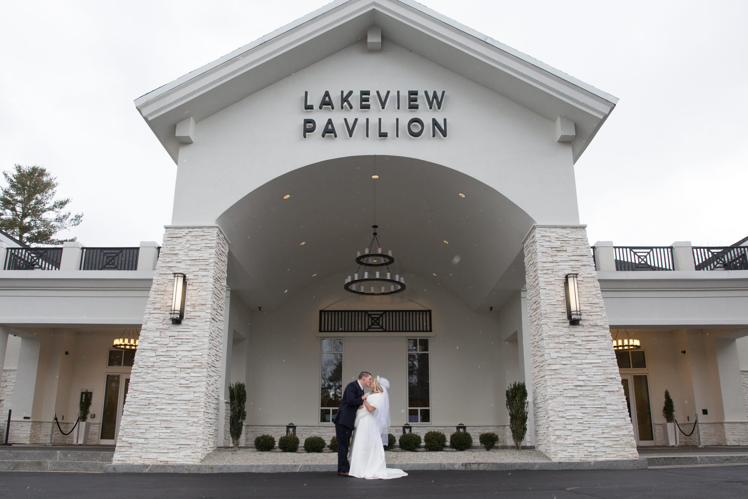 Bride and groom kiss outside the entrance to Lakeview Pavilion in Foxboro MA.