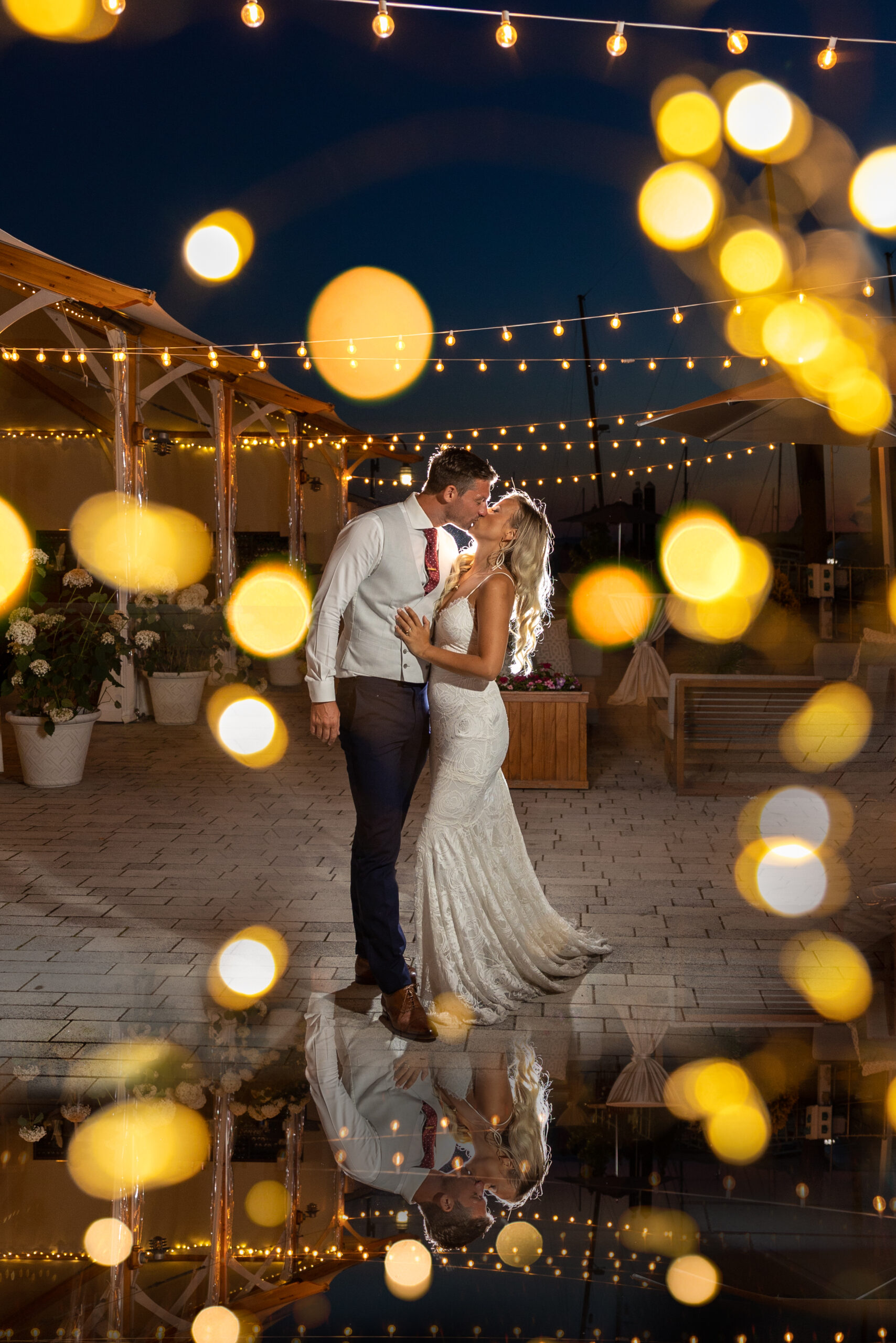 The bride and groom kiss under the twinkle lights outside the reception tent at the Bohlin in Newport.