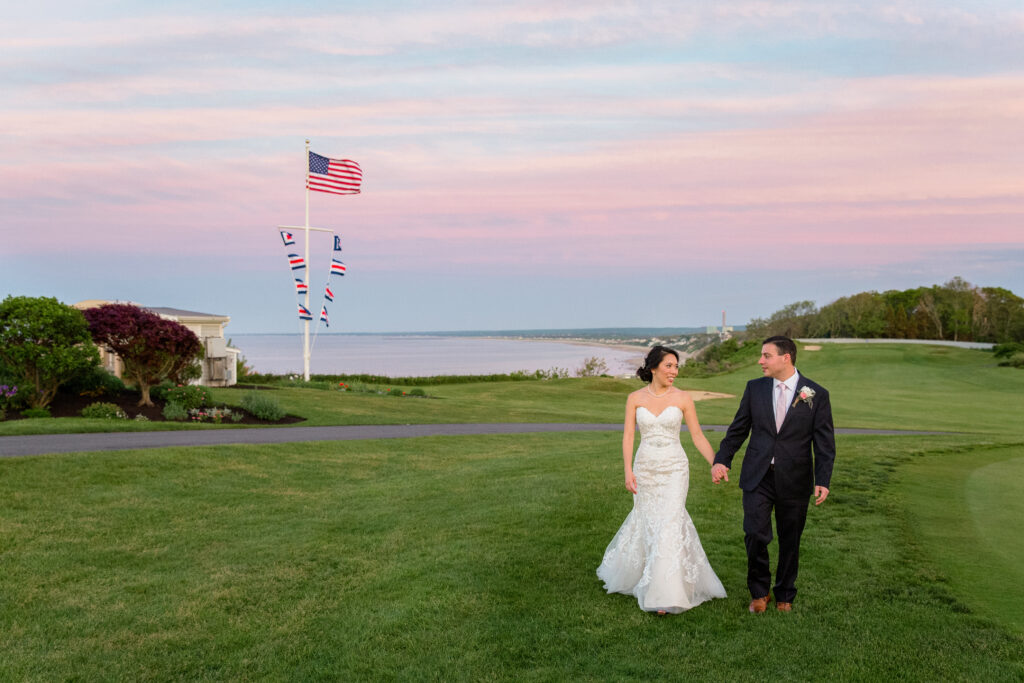 Bride and Groom stroll on the lawn of White Cliff Country Club during sunset