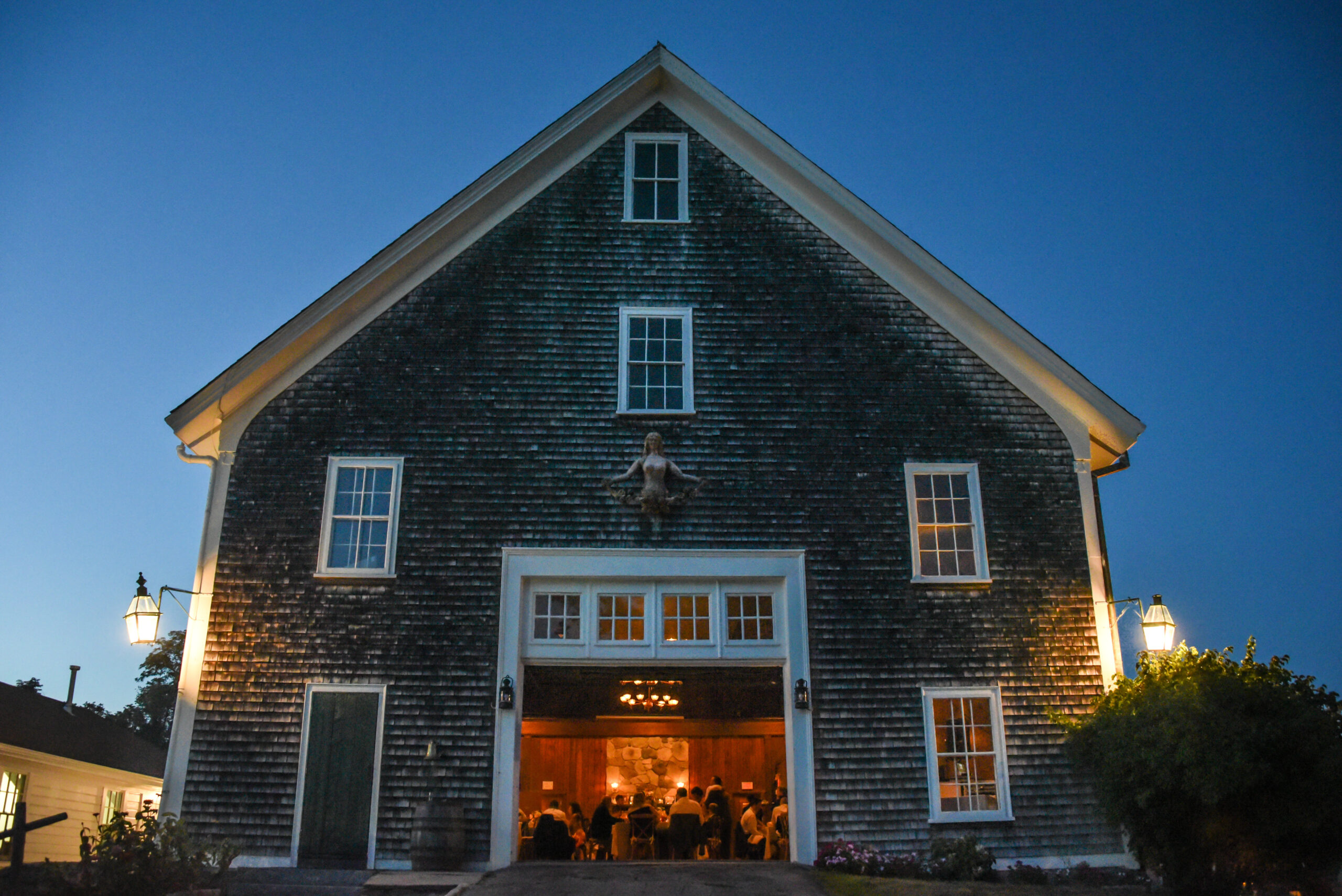 The Barn at Mount Hope Farm glows in the blue light of dusk, during a wedding reception.