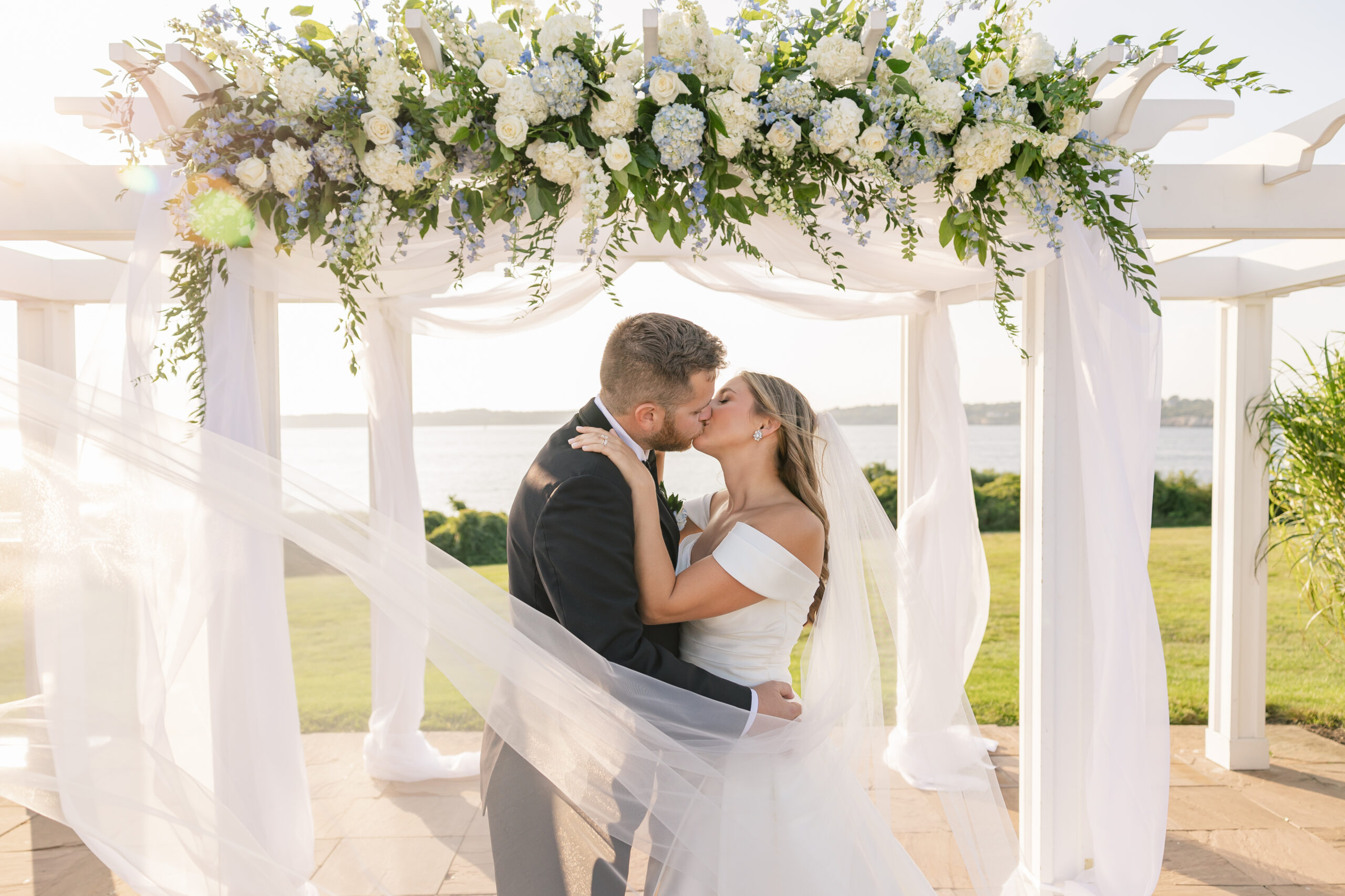 A bride and groom kiss under a beautiful coastal chuppah at OceanCliff Hotel