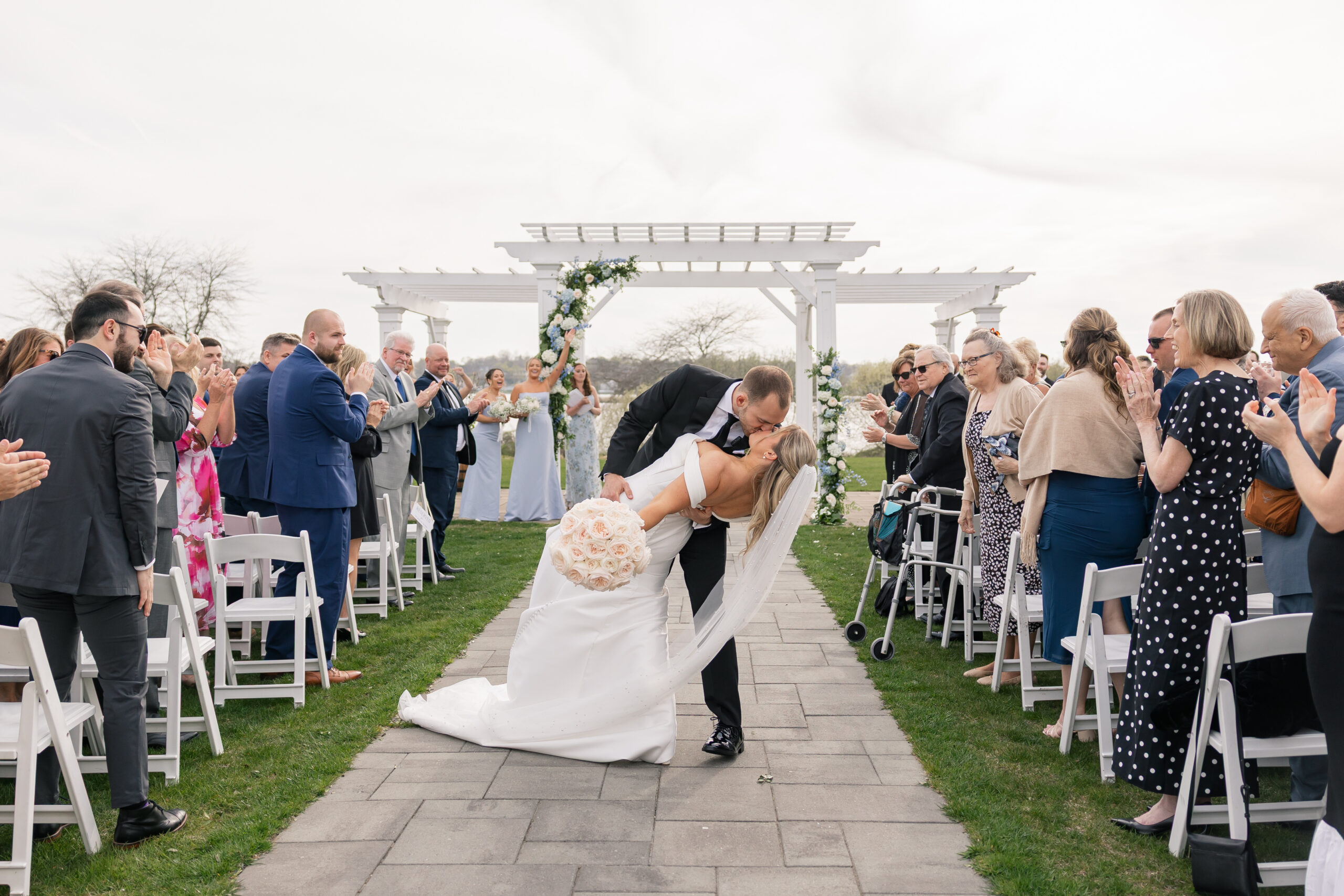 A bride and groom kiss at the end of the aisle at their outdoor wedding ceremony at the Wyndham Newport Hotel in Middletown RI